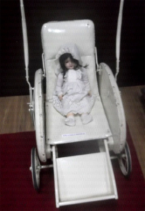 Кукла в игрушечной коляске